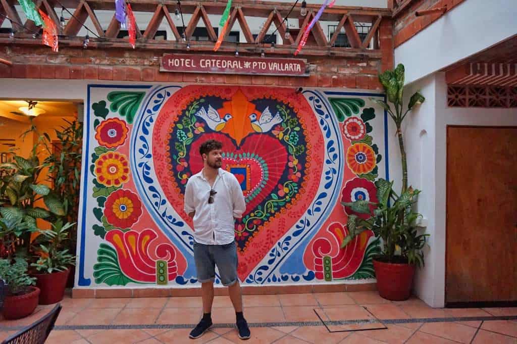 Chris posiert vor einer Wandmalerei im Hotel Catedral Vallarta