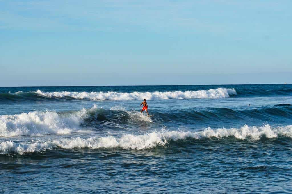 Ein kleiner Junge surft auf den Wellen vor Sayulita