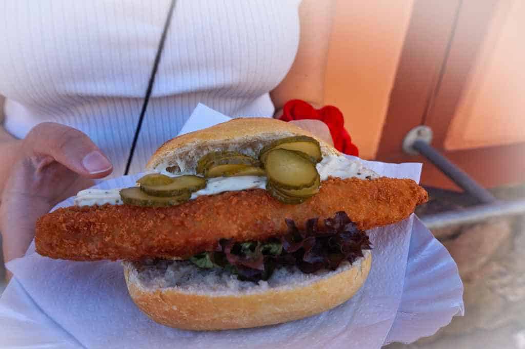 Marie hält ein Fischbrötchen mit Backfisch in der Hand