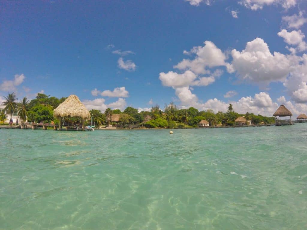 Die Lagune Bacalar mit Blick auf die Hütten und bewachsenen Uferböschungen