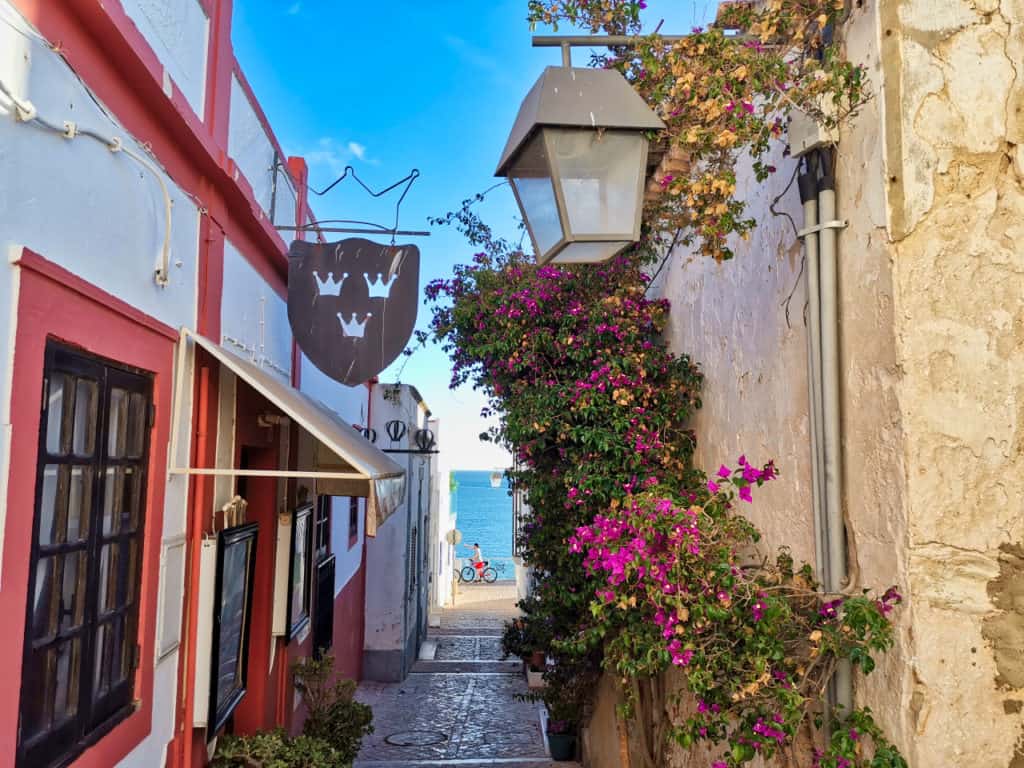 Eine Seitengasse in Albufeira mit schönen Blumen und antiken Lampen in Portugal