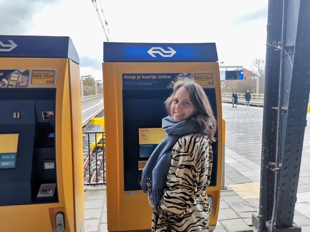 Marie steht am Ticketautomat im Bahnhof von Zandvoort auf dem Weg nach Haarlem.