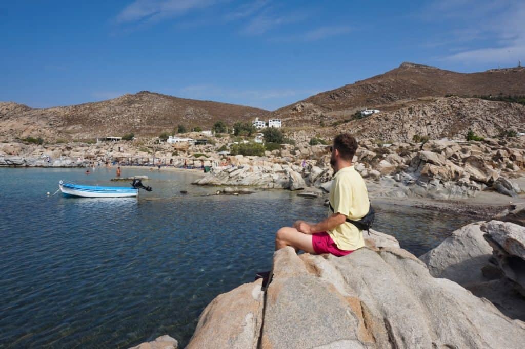 Chris sitzt auf einem Fels am Kolymbithres Strand auf Paros.