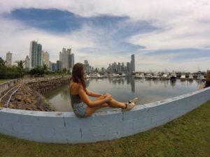 Marie sitzt vor der Skyline von Panama City am Hafen