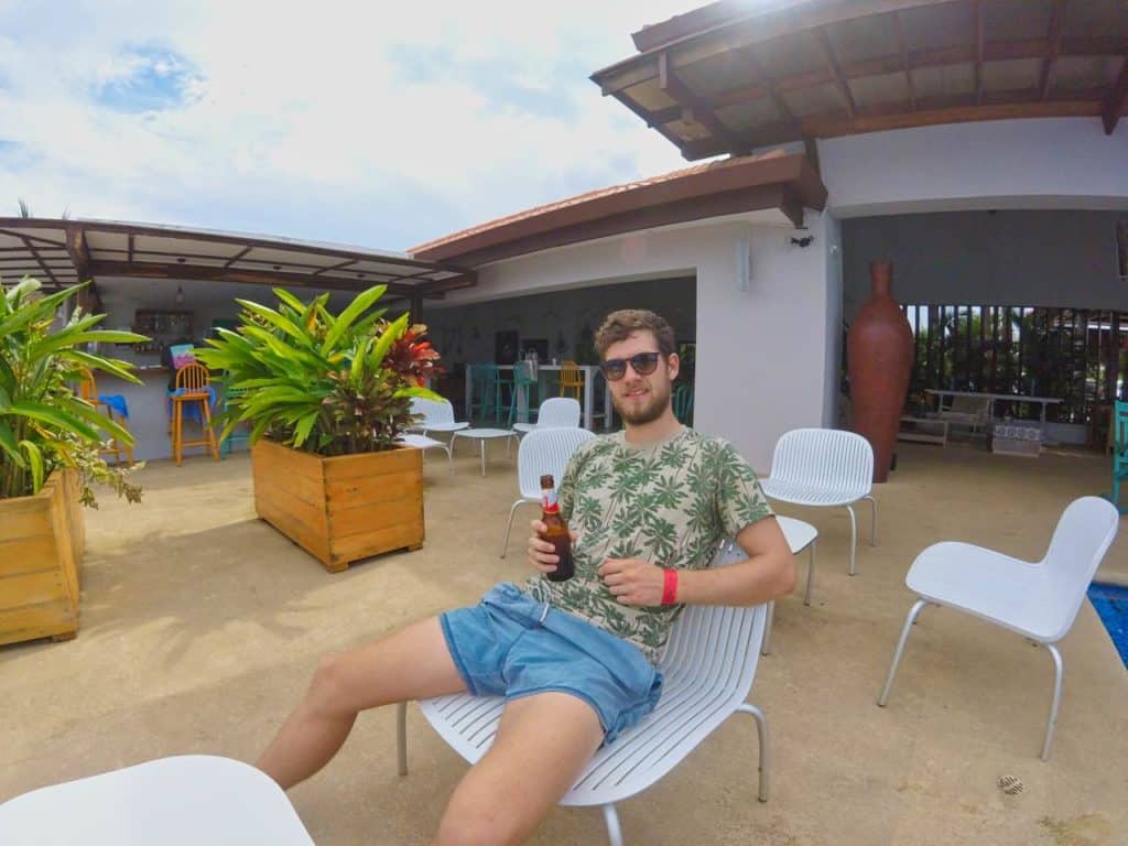 Chris trinkt ein Bier im Beach Club in Pedasi mit einem Bändchen vom Selina Hostel