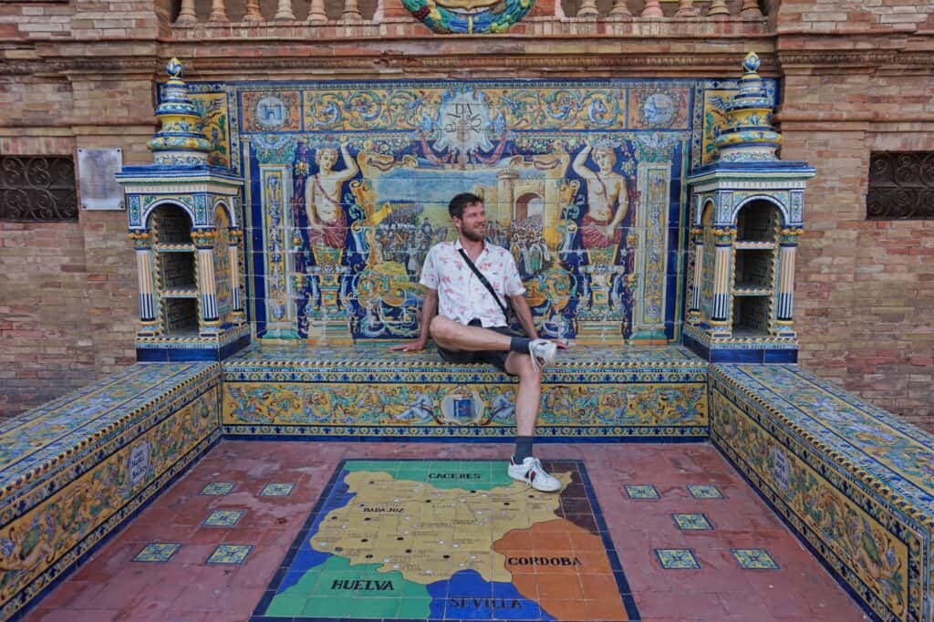 Chris sitzt auf einer Bank am Plaza de España in Sevilla, Andalusien.