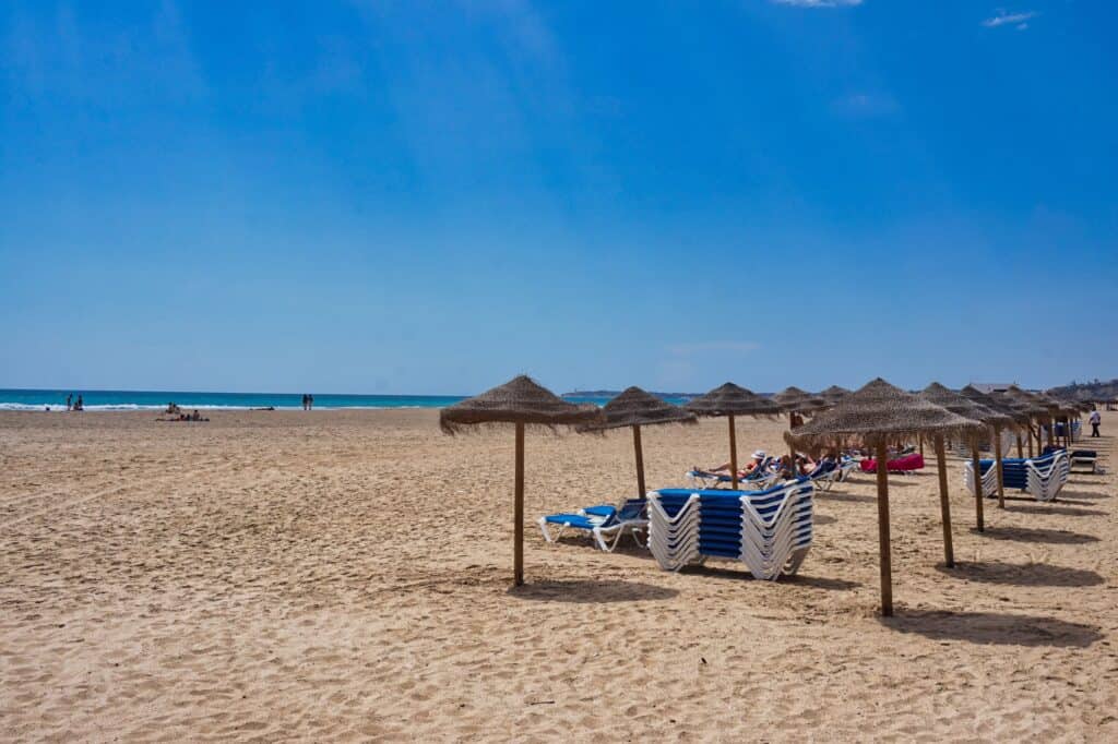Sonnenschirme am Sandstrand am Playa de los Bateles an der Costa de la Luz bei Conil de la Frontera in Spanien.