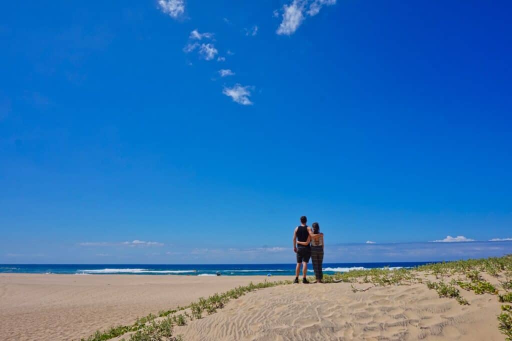 Marie und Chris stehen bei ihrer 3 Wochen Rundreise durch Südafrika am Strand und beobachten das Meer