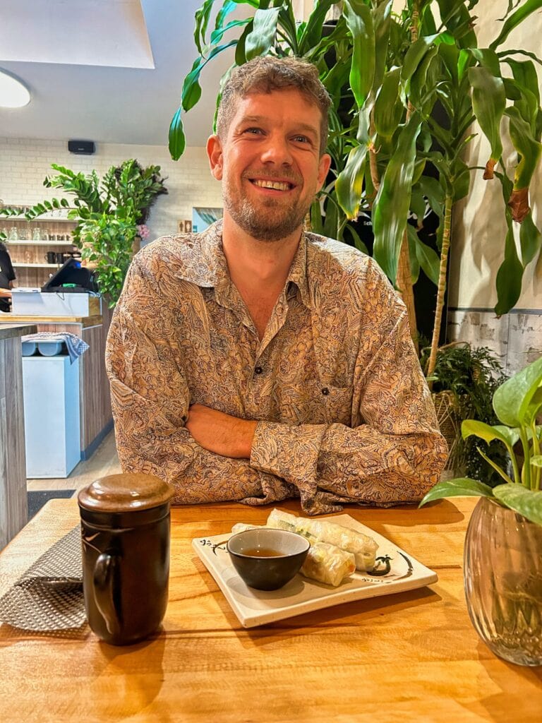 Chris sitzt vor einem Tee und vietnamesischen Sommerrollen im vietnamesischen Restaurant Yame in Köln.