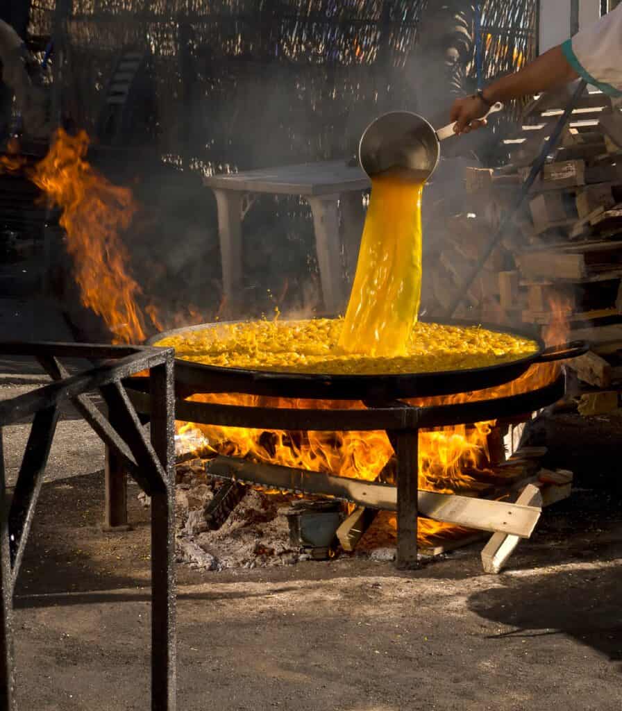 Paella wird über offenem Feuer am Playa Burriana in Nerja bei Malaga zubereitet.