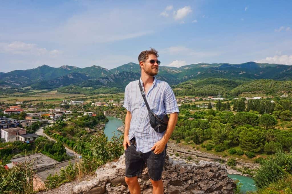 Chris steht in Permet auf dem großen Stein und genießt die Aussicht über den Vjosa River