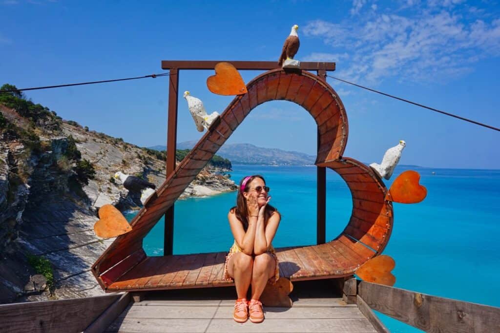 Marie sitzt in einem Herz an der Küste von Ksamil in Albanien