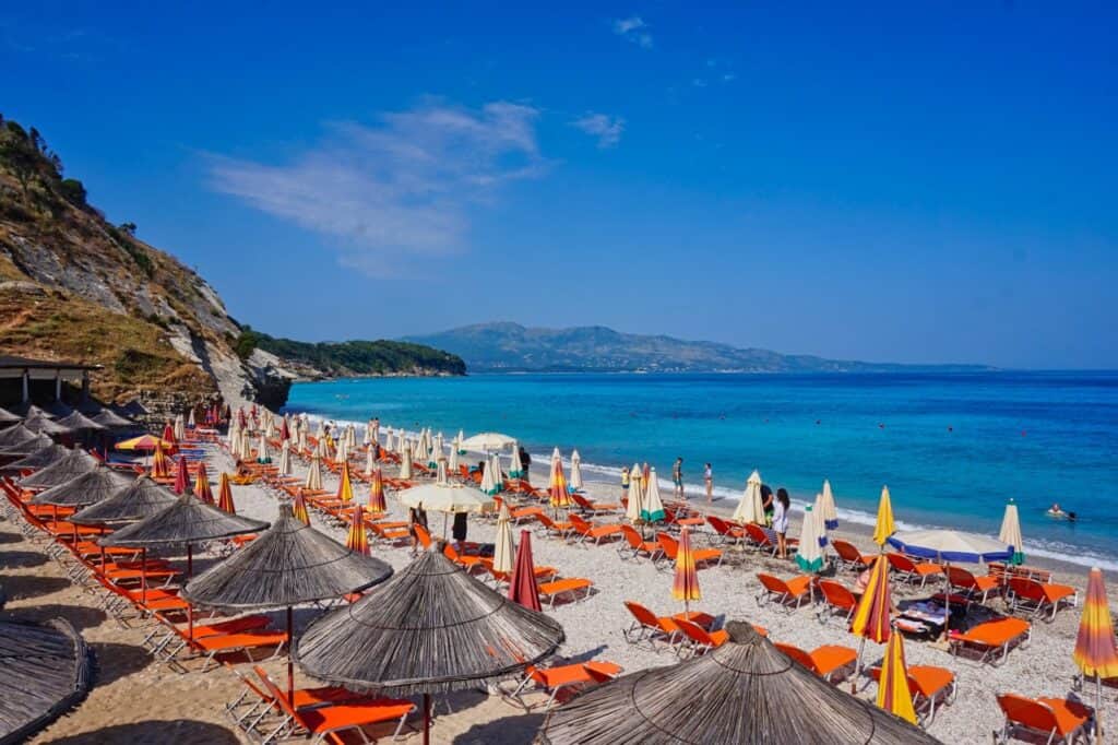 Orange Liegen und Schirme am Plazhi i Pasqyrave Strand in Ksamil