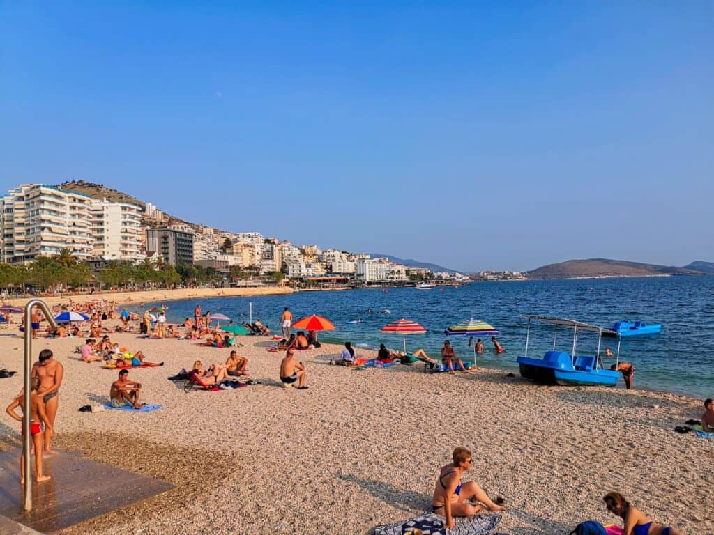 Viele Menschen sonnen sich bei strahlendem Sonnenschein am Saranda Beach