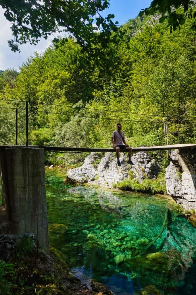 Chris sitzt auf einer Brücke auf dem Weg zum Blue Eye von Theth.