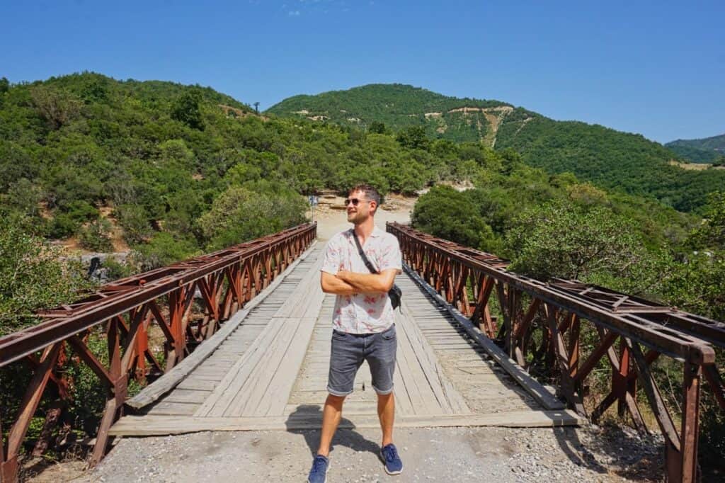 Chris steht auf einer wackligen Brücke über den Osum Canyon, die du unseren Erfahrungen nach nur mit einem 4x4 Mietwagen in Albanien befahren solltest