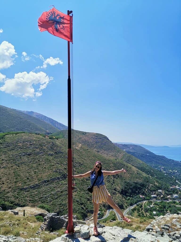 Marie steht an einer albanischen Flagge und denkt über die Albanien Einreise nach