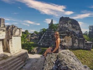 Marie sitzt auf einem Tempel am Plaza Mayor in Tikal Guatemala