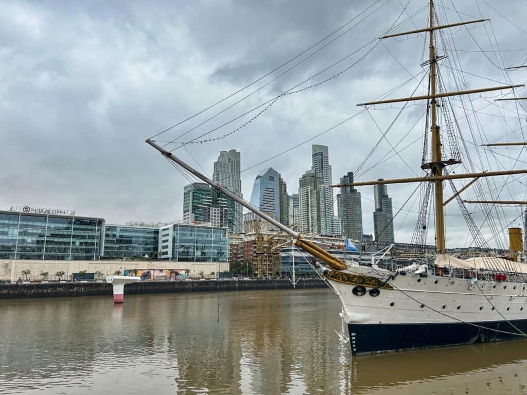 Boot im Hafenbecken mit den schillernden Hochhäusern von Puerto Madero, Buenos Aires im Hintergrund.