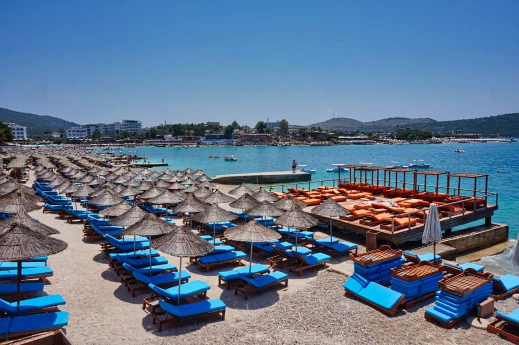 Liegen und Sonnenschirme an einem vollen Strand in Ksamil, Albanien nahe Saranda.