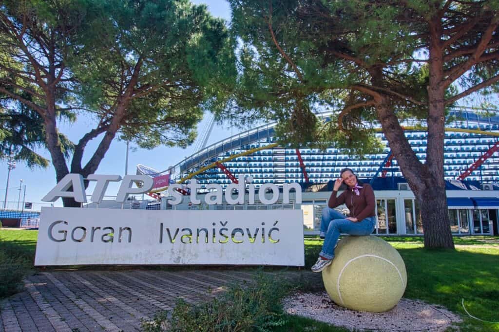Marie sitzt auf einem riesigen Tennisball neben dem ATP Stadion in Umag