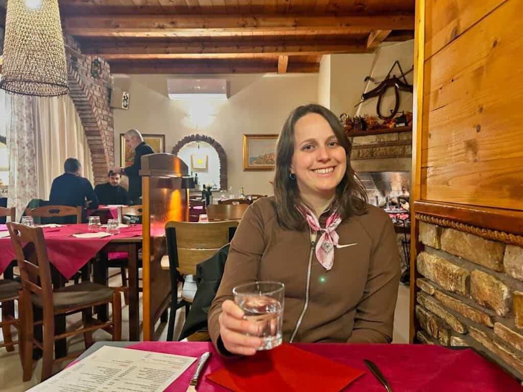 Marie sitzt in der Konoba Jure, hinter ihr erkennt man das Feuer auf der rechten Seite, über dem in diesem Restaurant in Rovinj das Fleisch zubereitet wird