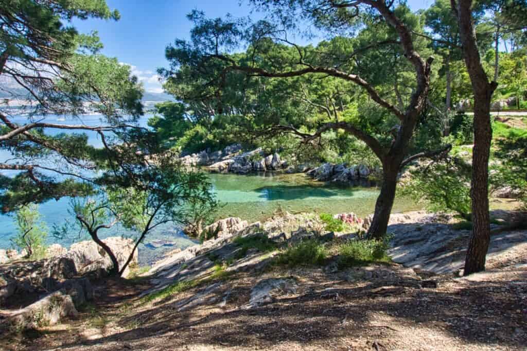 Blick durch Bäume auf die schöne Bucht des Third Water Beach in Split