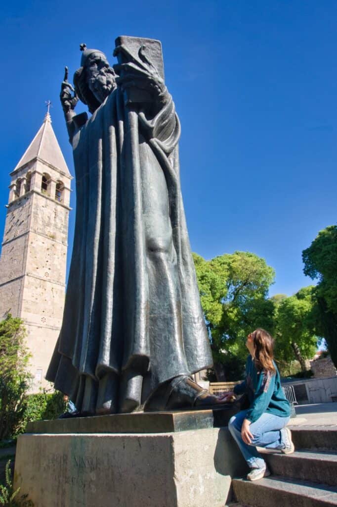 Marie reibt den großen Zeh der Statue von Gregor von Nin für Glück