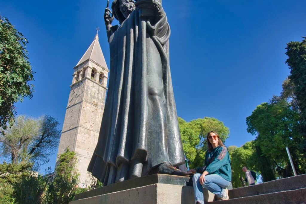 Marie fasst den Zeh der Statue von Gregor von Nin an und denkt darüber nach wie viele Tage man in Split bleiben sollte