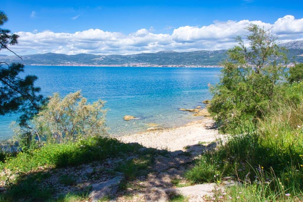 Blick auf den kleinen Kiesstrand Mary's Beach mit einigen Bäumen rundherum