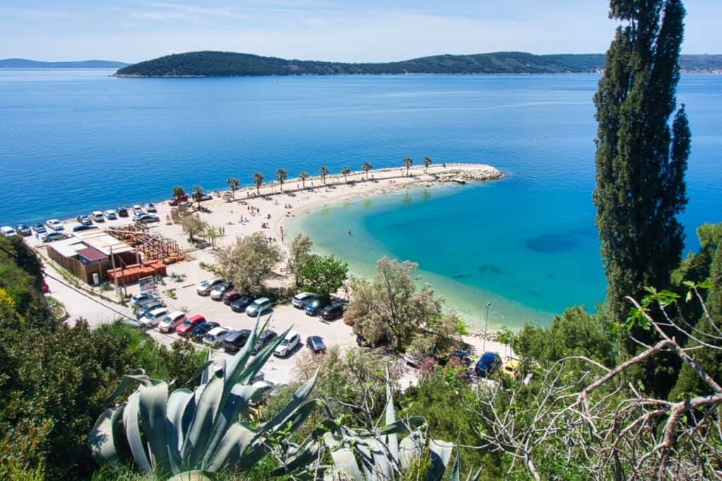 Ein Blick von oben auf einen Split Strand mit Palmen und kristallklarem Wasser