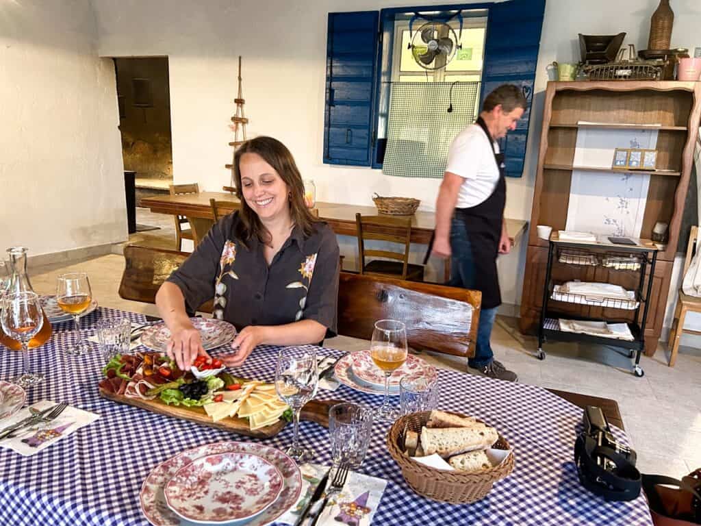 Marie sitzt bei Agroturizam Anin Dvor am Tisch und nimmt sich etwas von der Vorspeisenplatte