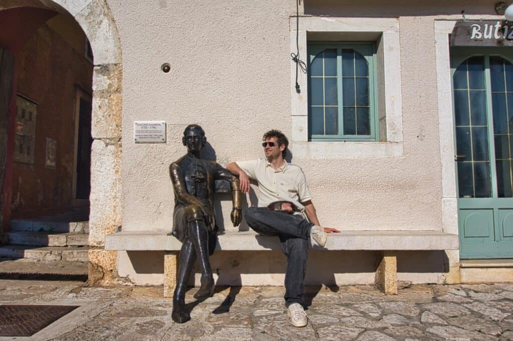 Chris vom Reiseblog Worldonabudget sitzt neben dem Casanova Denkmal, dem Wahrzeichen von Vrsar.