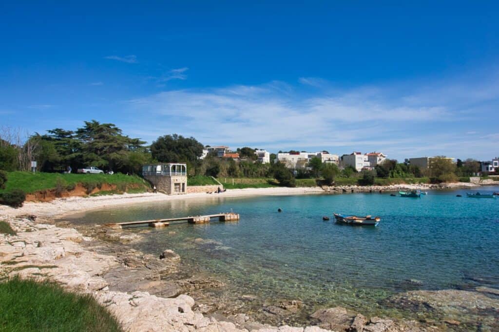 Ein sehr schmaler Strand in Pula mit Booten, die im Wasser liegen