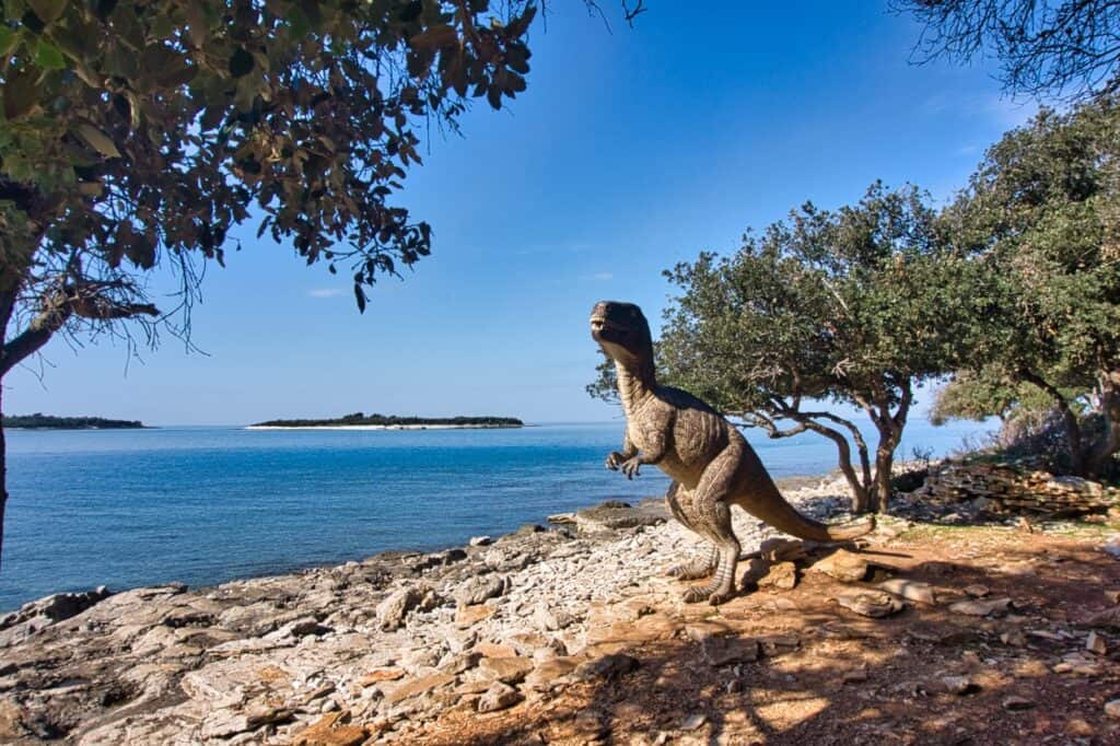 Dinosaurierfigur neben Dinosaurierspuren im Brijuni Nationalpark.
